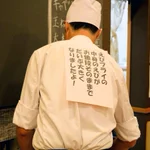 スペースの有効活用？とんかつ屋さんの店長。何故か背中に張り紙をしてお仕事中。