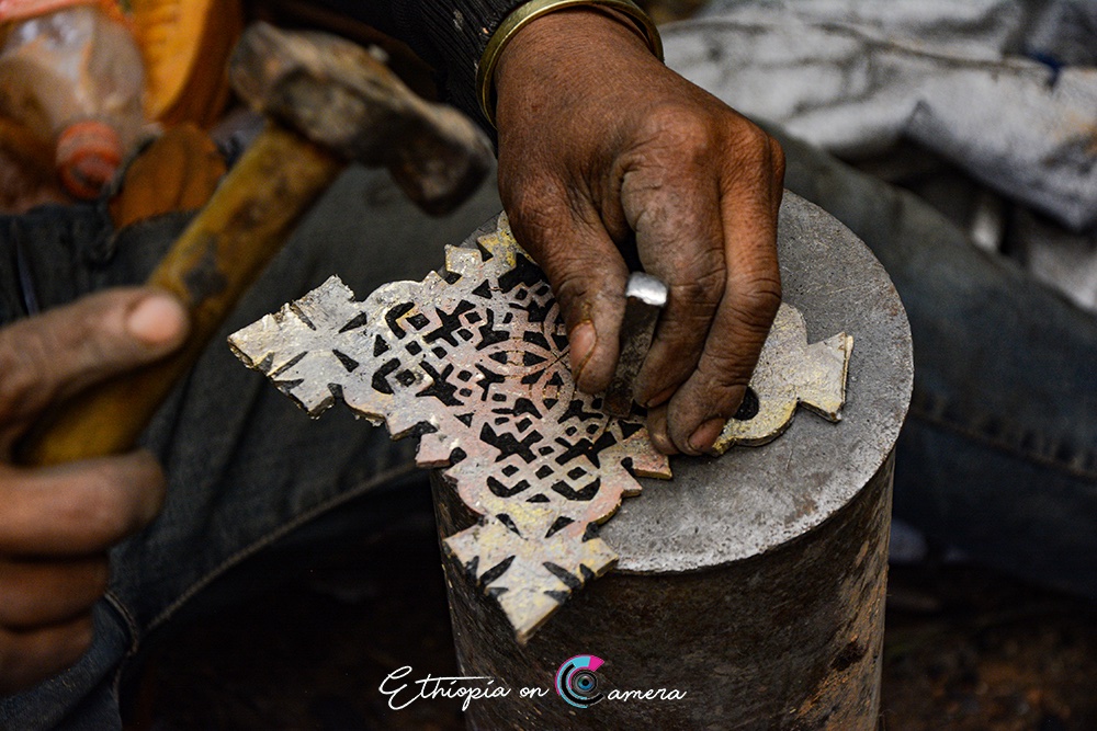 5/5 Liquid metal is poured into the empty mold and left to cool and harden. Later, the clay exterior is broken open, revealing the finished cross beneath.Once it has cooled down, the cross is first filed smooth and its frame are further ornamented with incised lines.