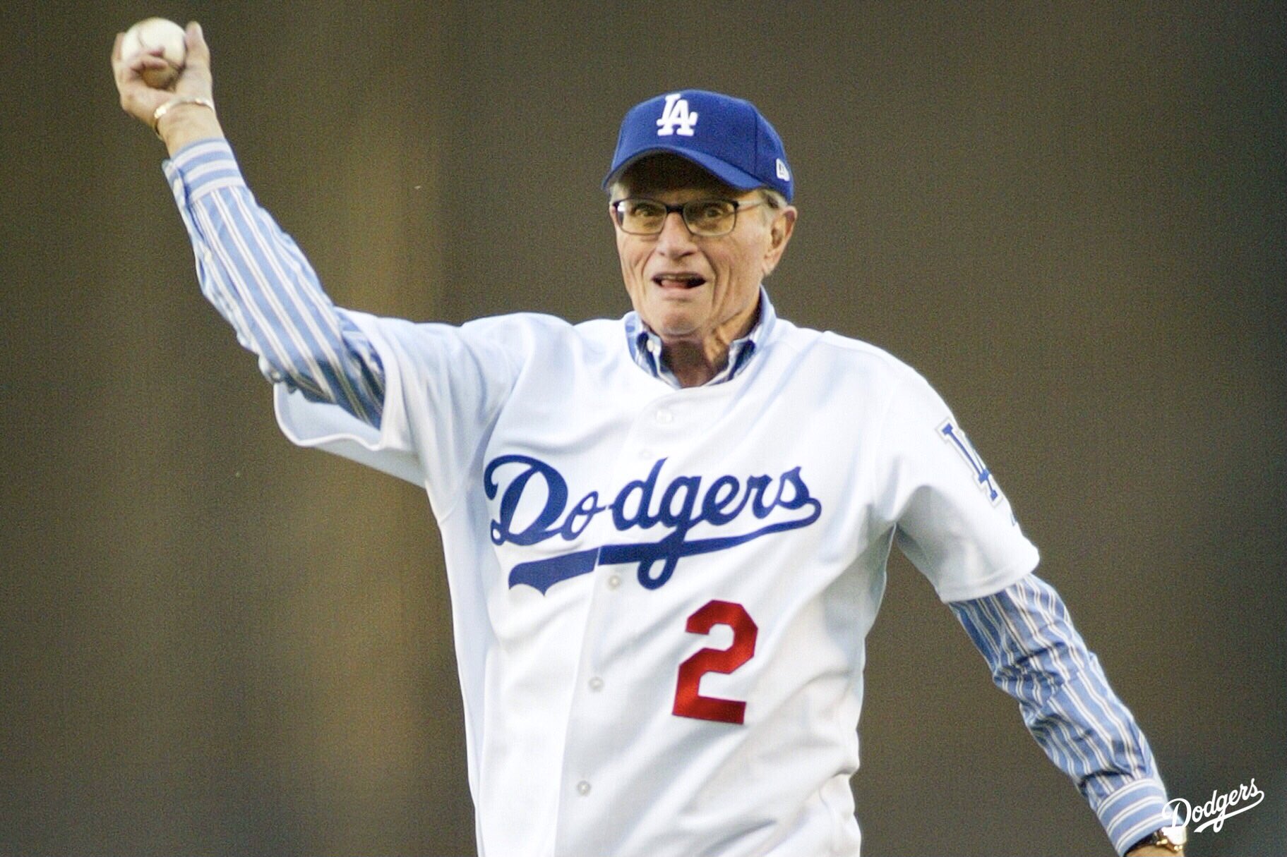 Larry King wearing a Los Angeles Dodgers jacket while outside a