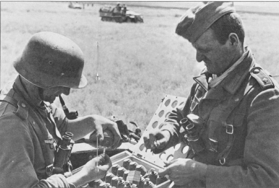 Those that are fused have been placed back in the box (nearest 2 rows), ready for use. The remaining 3 rows are upside down & to be fused. Fuses came in the following colours/times;Red cap = 1sec (smoke/booby trap)Blue = 4.5s standard Yellow = 7.5sGrey = 10s54b)