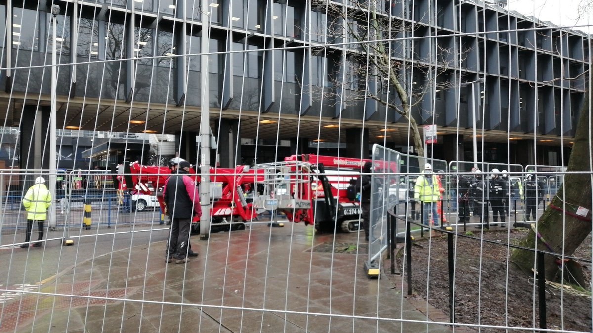 Cherry pickers assembling.Looks like they're going to tackle the protesters in the trees first.