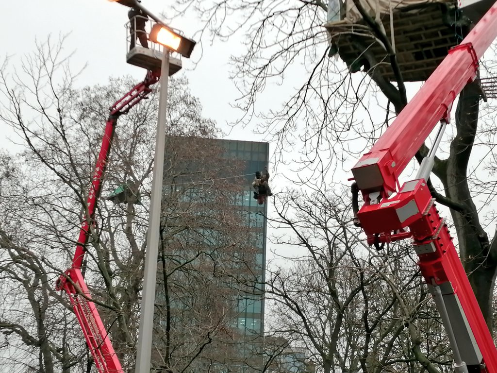 One of the male protesters wearing a balaclava has ziplined out of the tree house and is now dangling in mid air