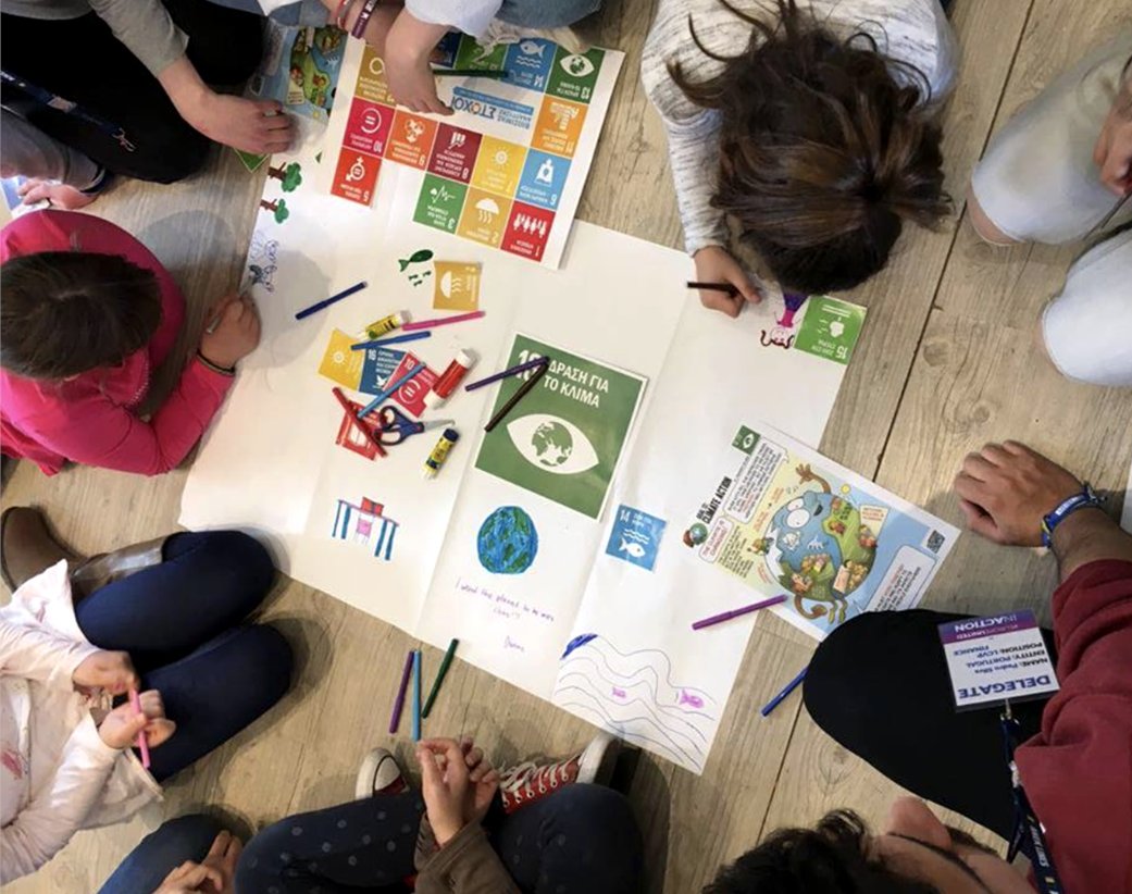 Children work together on a poster for Global Goal 13, Climate Action
