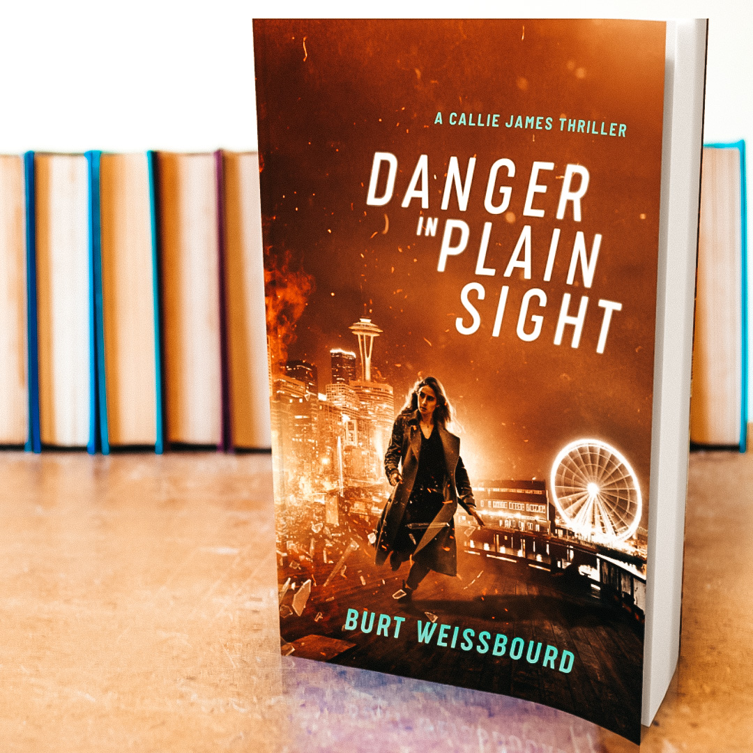 Danger in Plain Sight book standing in front of a row of books lined up.