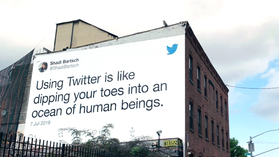 Billboard in NYC of a Tweet that says: Using Twitter is like dipping your toes into an ocean of human beings.