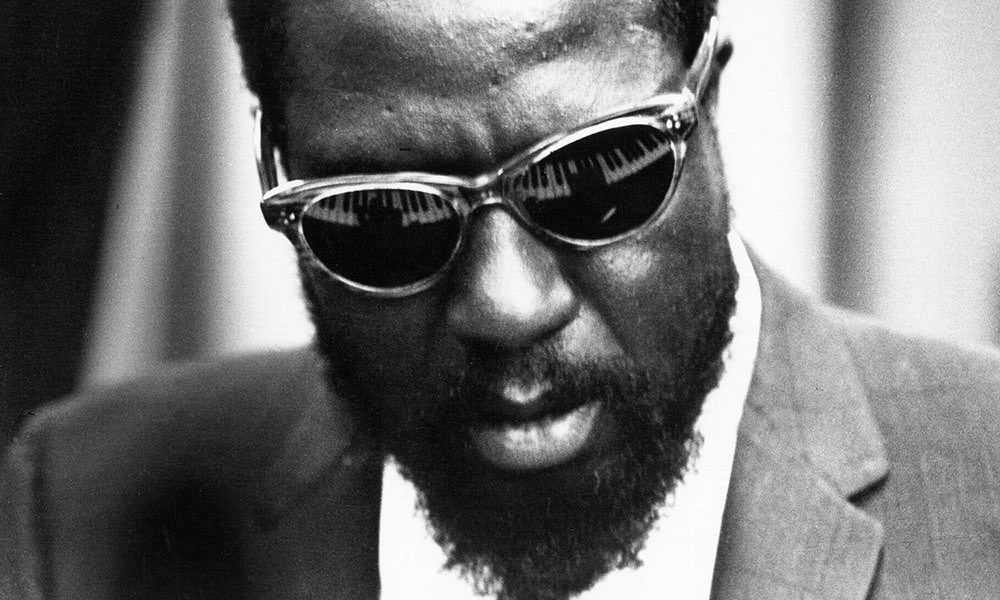 Thelonious Monk with a piano reflected in his sunglasses.