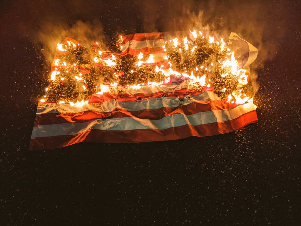 An American flag burns in the mddle of the street
