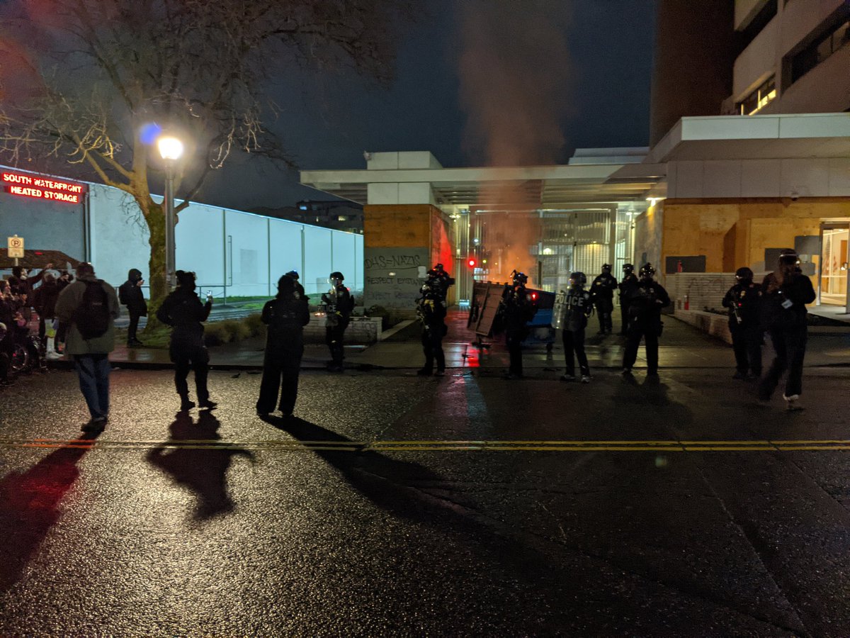 Protesters forming back up. Chanting. At the crosswalk maybe 30 feet from the driveway. Some press closer