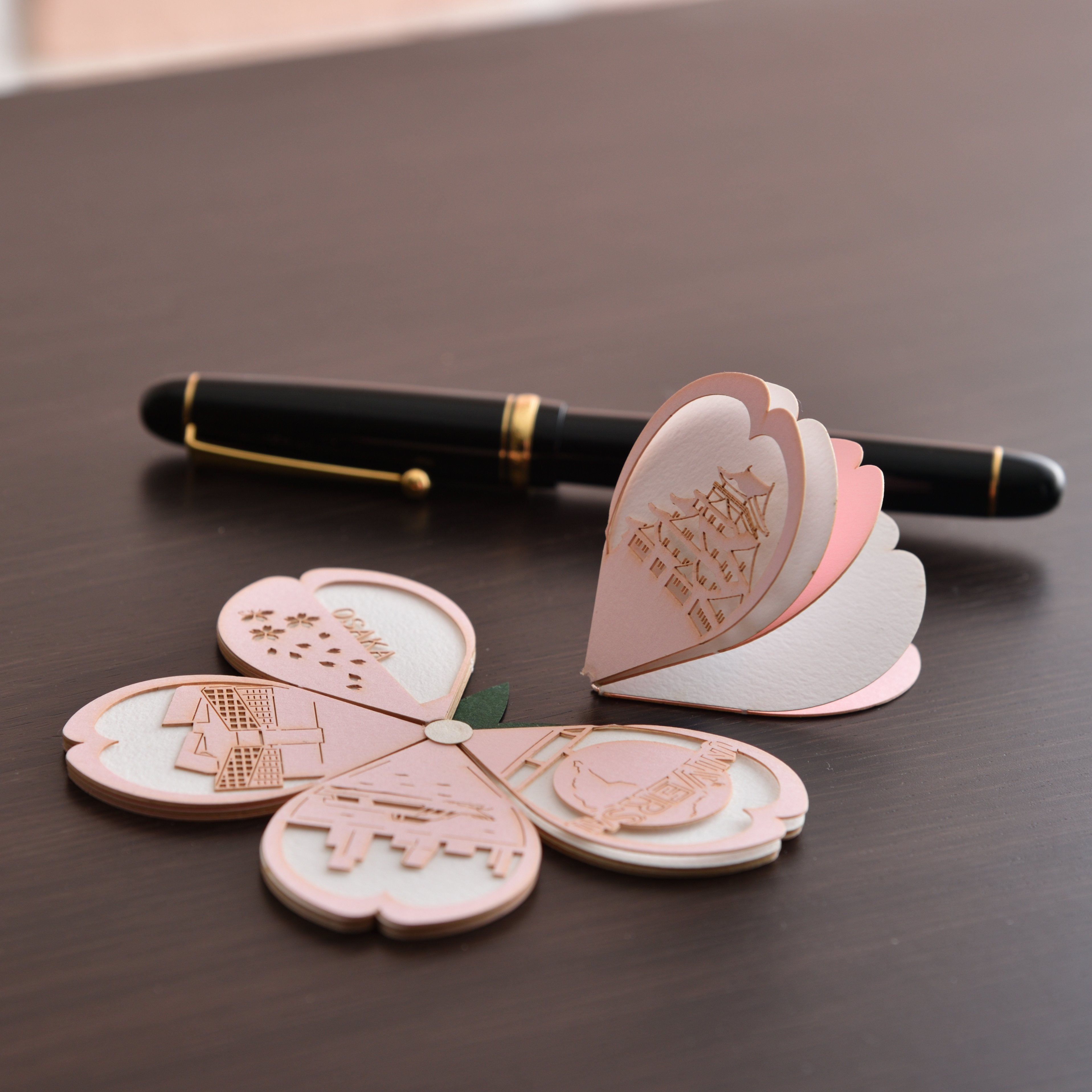 大阪商品計画 大阪産業局 緻密な模様をあしらった花びらメッセージカード Omoshiroi Petals 桜 株式会社トライアード 桜の花びらをかたどった紙を引っ張るとプチンと切り取れ 花びらを開くと満開の桜が出現する 不思議なカード 展開した花びら4枚には