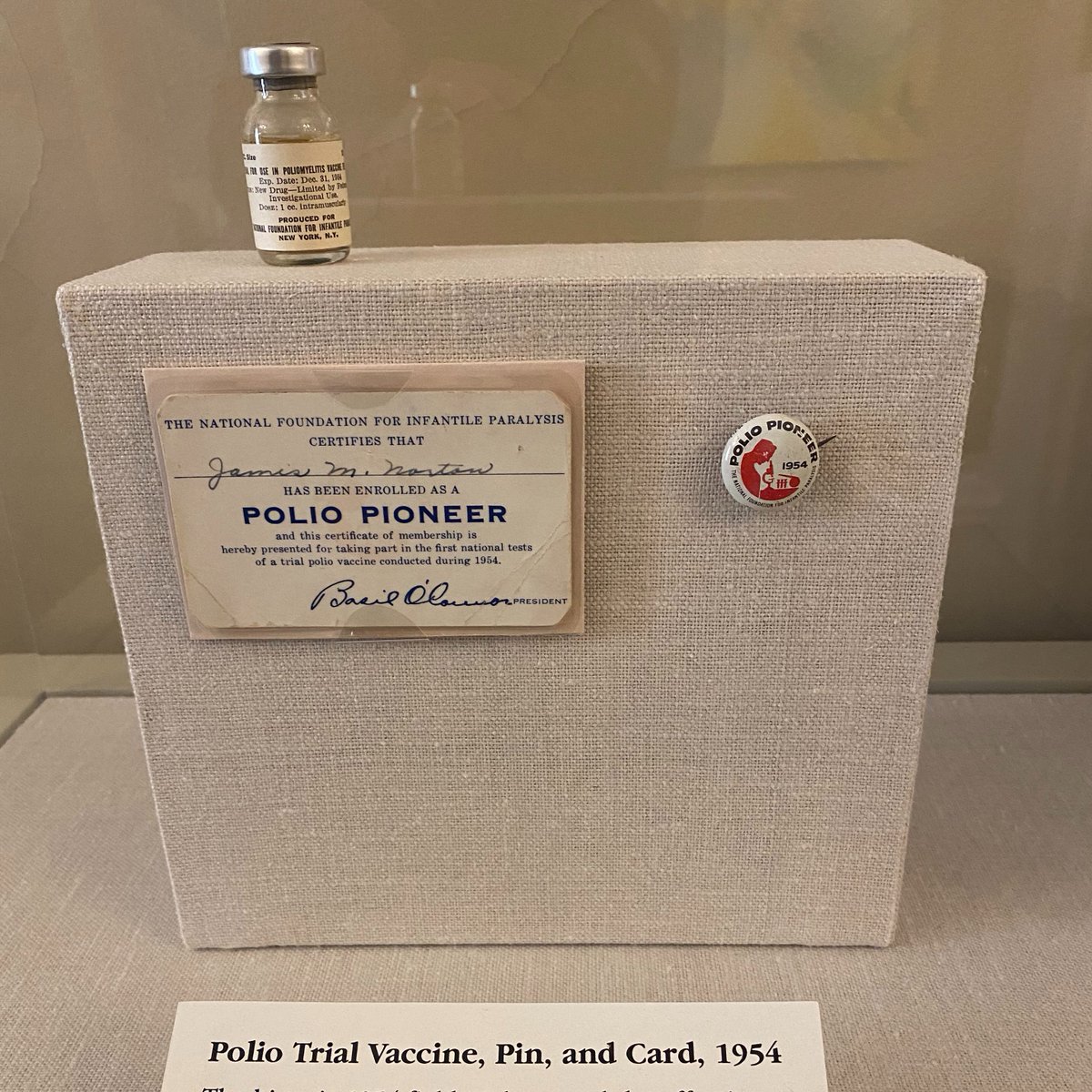 On display steps from my desk at the Smithsonian Castle is a vial from the 1954 trial of the polio vaccine. From the collection of our  @amhistorymuseum, the story of the development of the vaccine is a good one. But I'm even more intrigued by the small pin beside it.