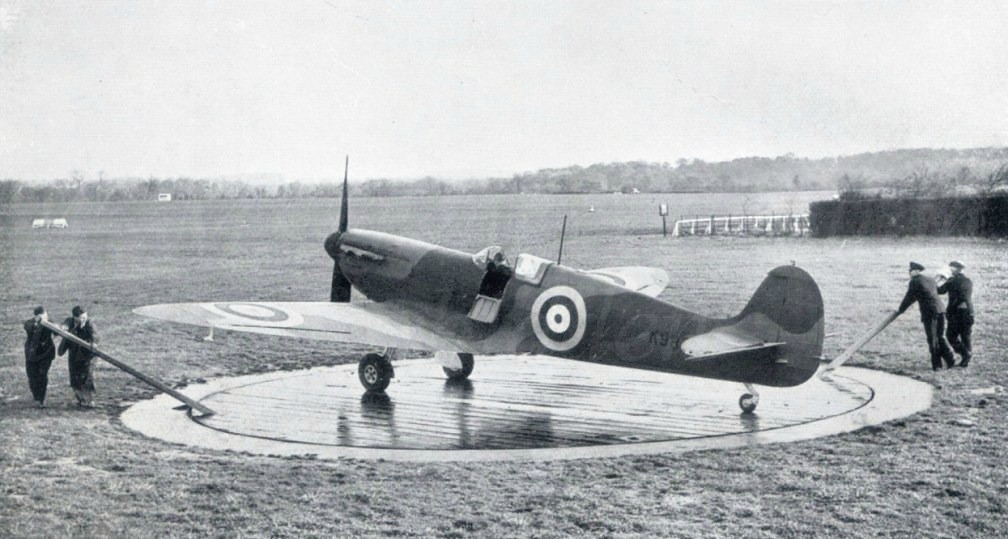 'Compass swinging' an early mark of Supermarine Spitfire in 1939. 
The base has markings for the local magnetic north, the aircraft is being aligned to this bearing, whilst an instrument fitter adjusts the on-board compass. A little known, but vital part of aircraft maintenance.