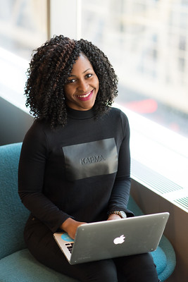 Black woman has a laptop on her lap. She is smiling. Photo is CC BY WoC in Tech Chat.