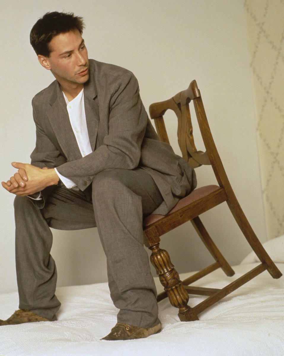 just keanu reeves sitting on a chair on a bed