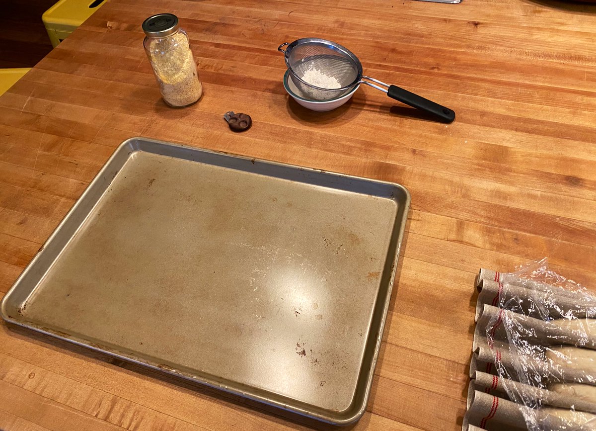 Here’s what you need ready next. Baking sheet, some semolina or cornmeal for nonstick, flour in a sieve for dusting, and a sharp AF blade for scoring. You’ll also need to have a couple good handfuls of ice or some hot water ready to put in the bottom of the oven for steam. Ready?