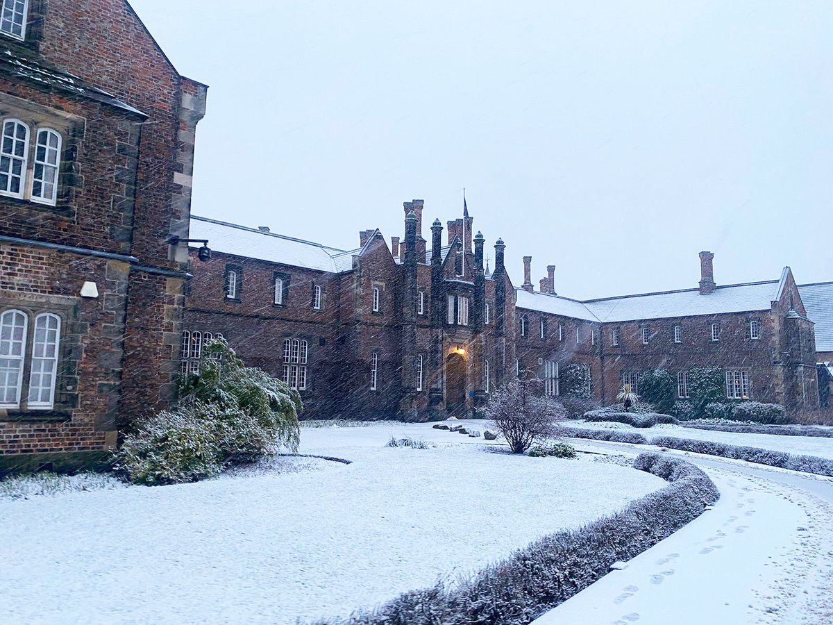 Landscape photo of the front of YSJ's campus, covered in snow with more flakes falling