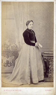 Between 1862-68 the crinoline cages, rather than being equally circular all the way round, shifted the emphasis to the back of the dress, as can be seen in KLNTY2020.130, KLNTY2020.166 & in the 1866 wedding photo of Northenders Thomas Senter & Elizabeth Bone [TY2007.6651]. [3/20]