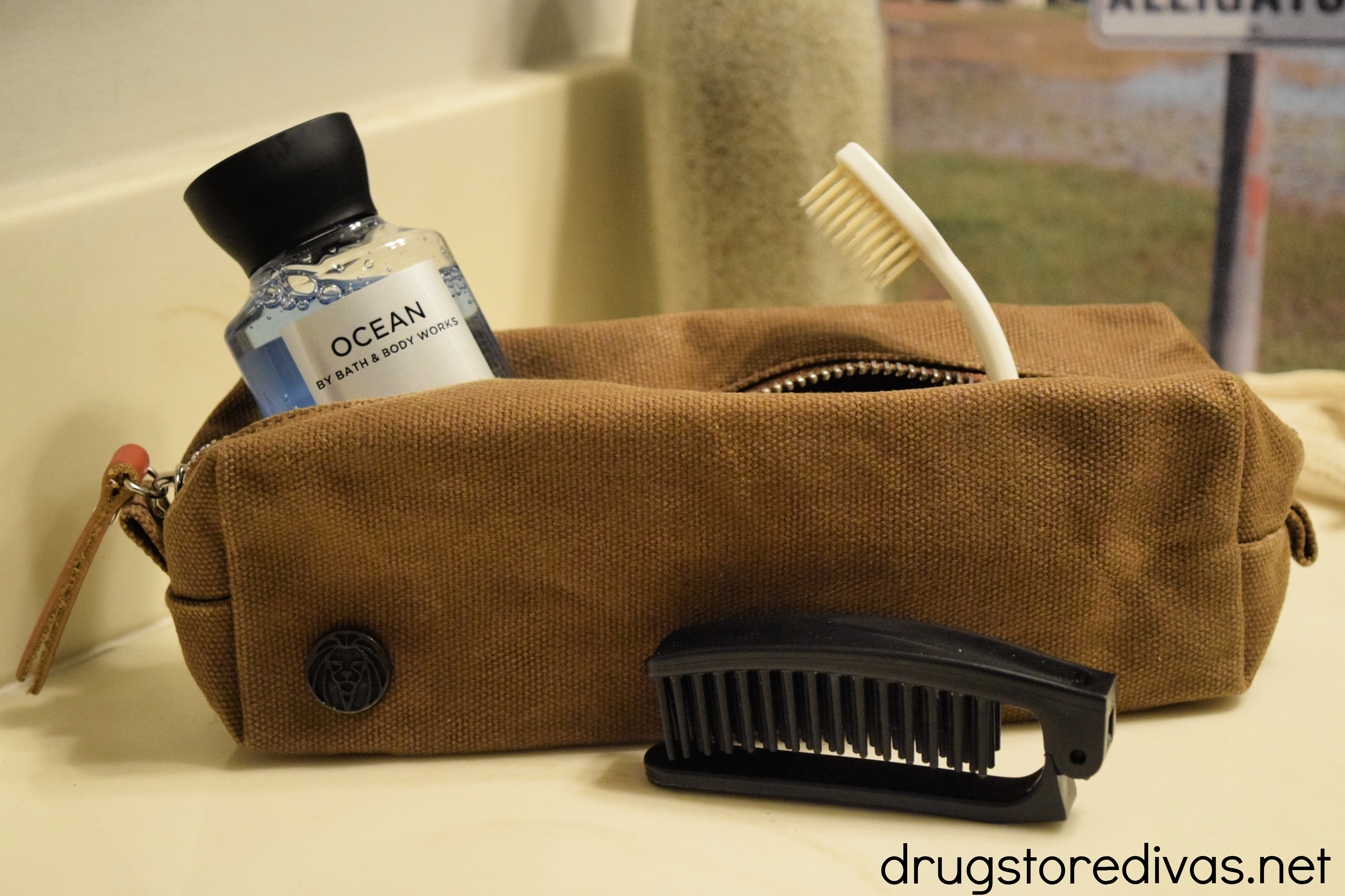 Travel bag with a brush in front and a toothbrush and body wash inside.