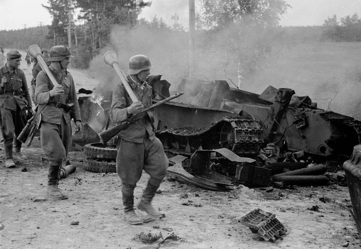 tarihlerle's tweet photo. Tali-Ihantala Muharebesi’nde enkaza dönmüş bir Sovyet T-34 tankının yanından geçen Fin askerleri. (Üzerlerinde anti tank ve Suomi KP/-31hafif makineli silahı görünmekte.) https://t.co/iyIQT6joZT