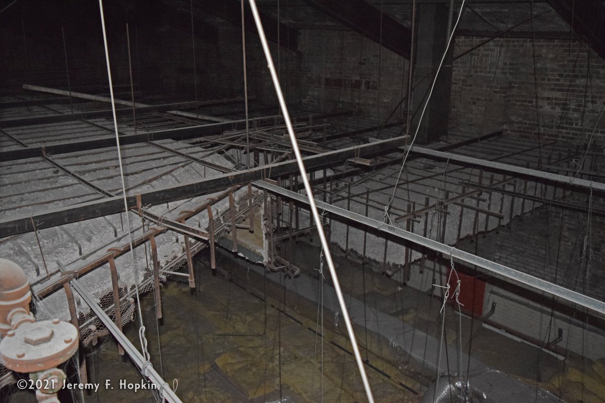 Swinging around the ironwork trusses like Tarzan, we approach the attic's north west corner. Looking over the edge we see a chunk of concrete suspended in midair; it's the ceiling of the stage that used to sit just behind the movie projection screen which was hung from here.