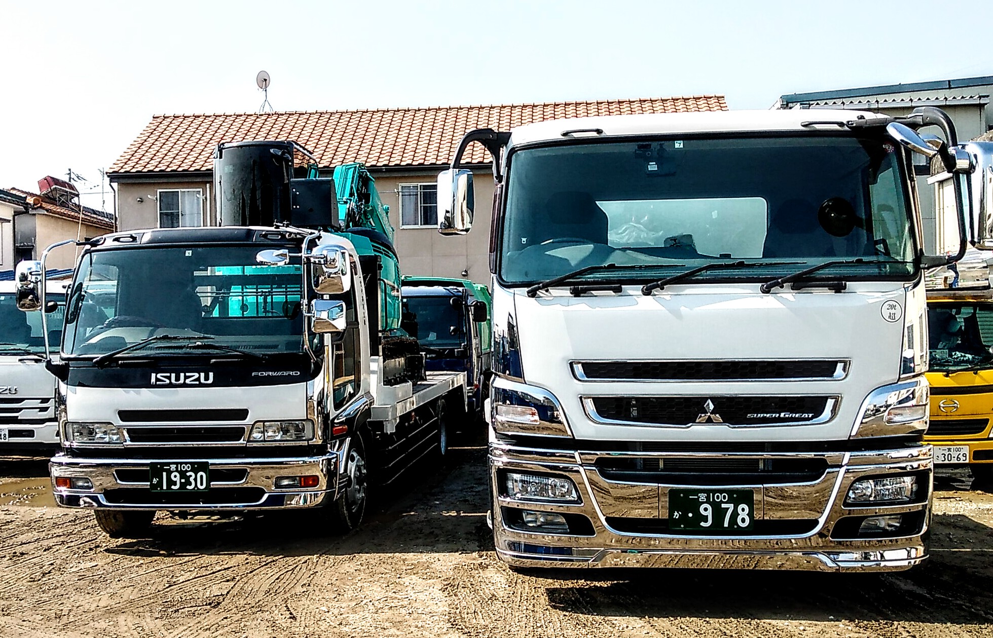 一宮中部衛生株式会社 自社所有の重機回送車 左側の三菱は１５トン積載のフルサイズ 右側のイスズは８トン積載の小型タイプ 使う 重機や搬入路の道端によって 使い分けをします 不思議な事に メーカーが違っても 何となく似ている感じがします