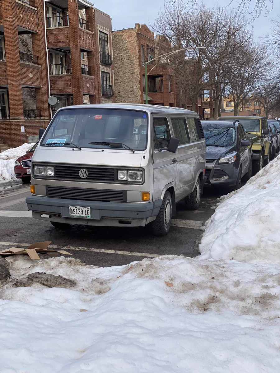 Photo of large gray Volkswagen van parked on street surrounded by snow