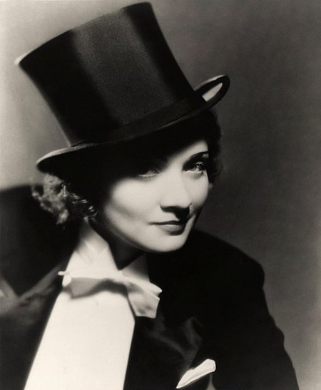 In the 1932 film Morocco, queer icon Marlene Deitrich is the first woman to share a same sex onscreen kiss. Dressed in a suit and hat, the kiss is met with laughter in the scene and would have been received as a comedy moment by audiences.