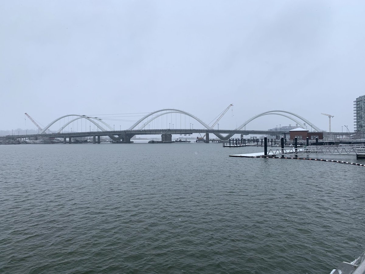 Frederick Douglass Bridge with six arches over water and underneath cloudy sky. 