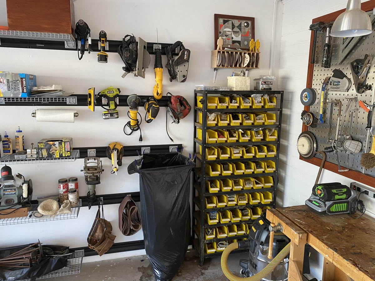On the south end of the east wall, I've hung power tools. These used to be on shelves, but I like being able to see and grab them more easily. Next to that is a small-parts rack I've had for 25 years. The black trash bag hangs on two brackets. I clamp it into place with 4 clamps.