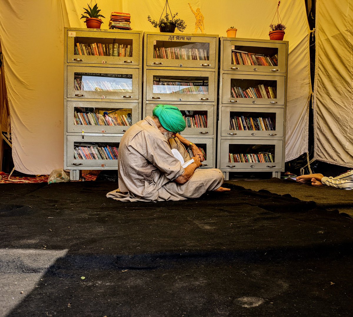 A farmer spends his morning reading at the makeshift library at #SinghuBorder
