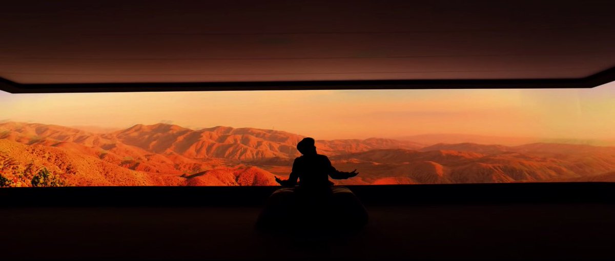 the walls fall away and he is on a bed in a dark room that showcases an orange view. this same room can be seen later on, when he is dancing around, but instead the room is blue and the view of the outside world is gone. it is as if the bed is his ticket to see what it’s like