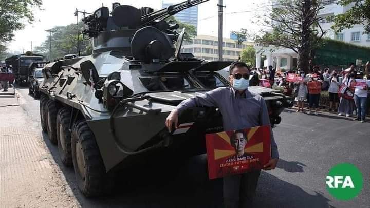 In front of the central bank of Myanmar, some people peacefully take a photo as a memory with military trucks that undertake security while people protest.