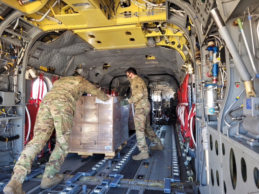 TXMilitary's tweet photo. Texas Soldiers load a Chinook helicopter with cases of food to be delivered to Texans in need. #TexansHelpingTexans https://t.co/CcwwCbg2uq
