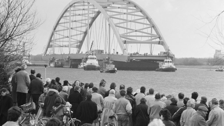 Rijkswaterstaat's tweet photo. Zie ginds komt de... tweede #VanBrienenoordbrug! 🛳️ Het transport van de nieuwe boog naar #Rotterdam trok duizenden toeschouwers. Op 25 februari 1989, 32 jaar geleden, werd de tweede brug op z'n plek gezet. Benieuwd naar de toekomst? 👉 https://t.co/HLHvwFI9Jw #ThrowbackThursday https://t.co/oKzBZnQa1A