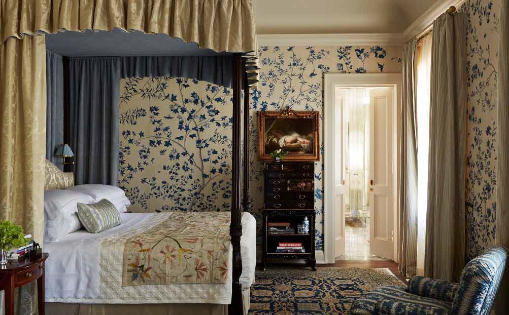 This bedroom is sumptuously outfitted with blue export wallpaper panels, beautiful nineteenth-century silk-embroidered linens, and a mahogany tester bed attributed to Gillows.
