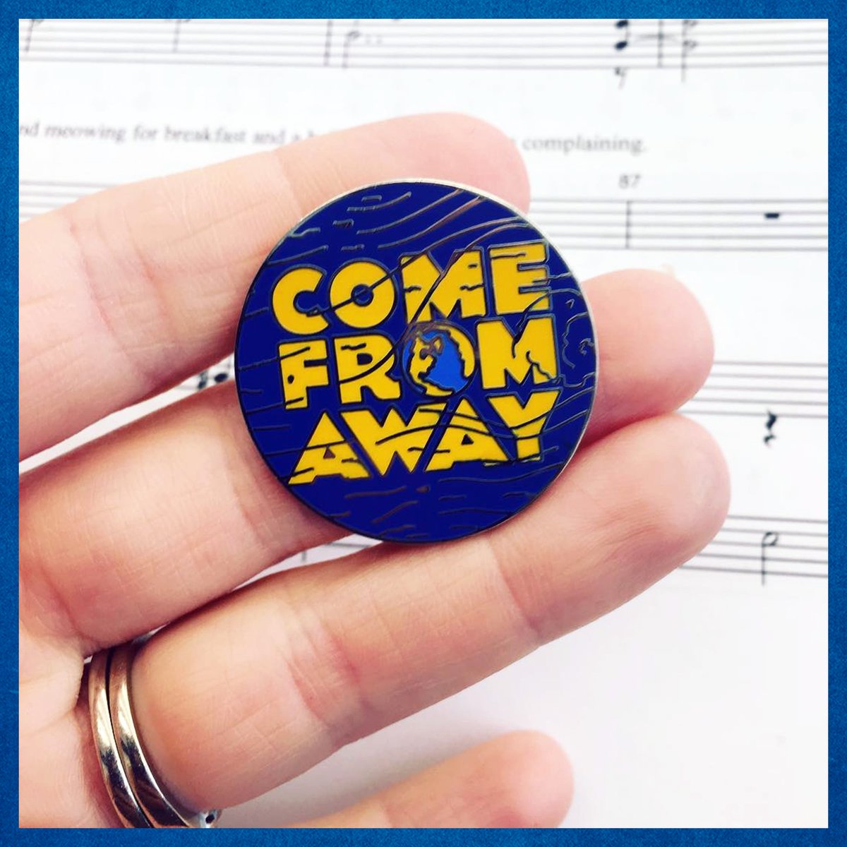 Come From Away pin held over Come From Away sheet music
