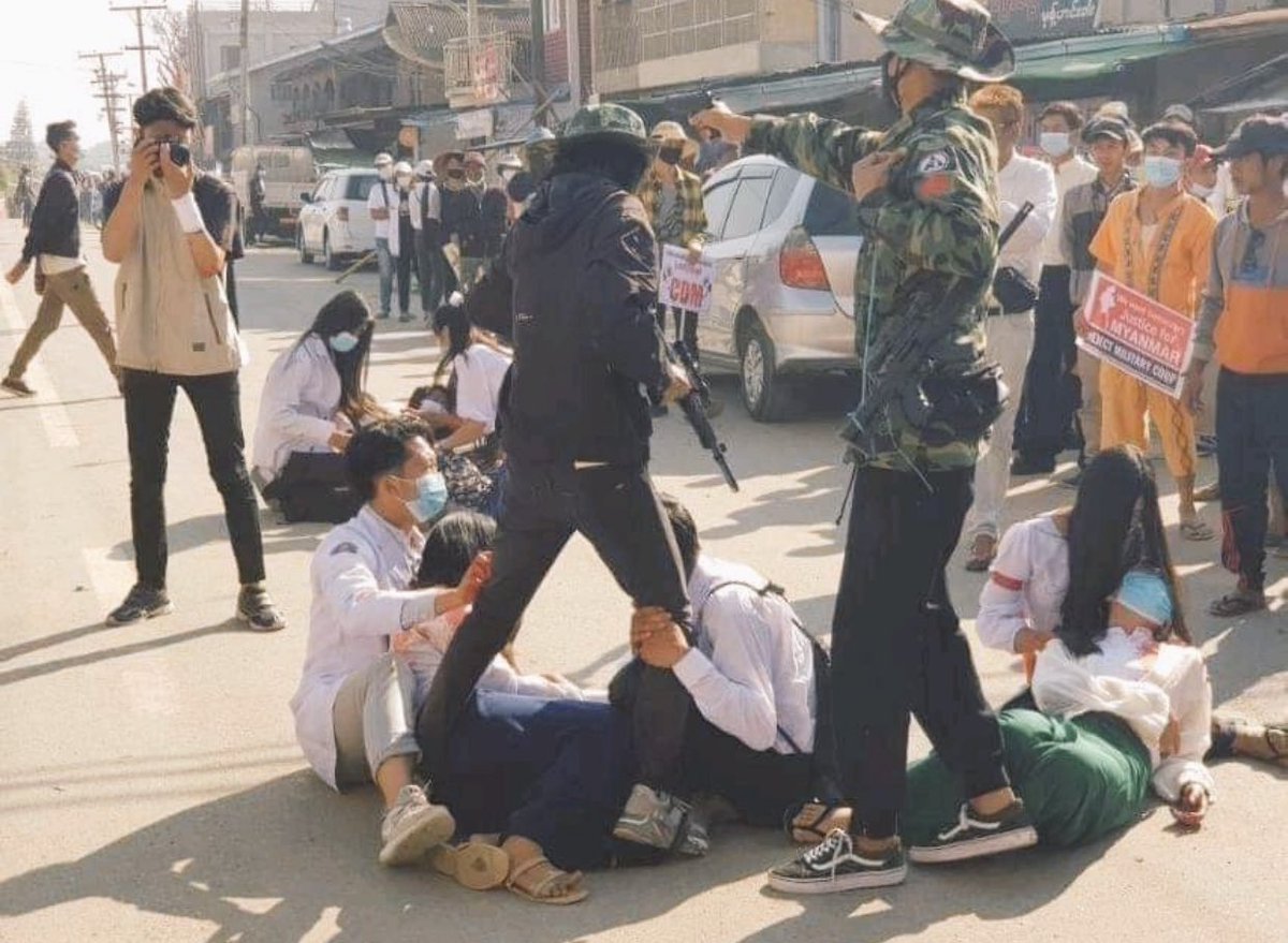 ManymarTimes's tweet photo. 仰光一名女学生背警察击中后，两位男同学紧紧拖住持枪军人，不让他走 https://t.co/889adORJfx