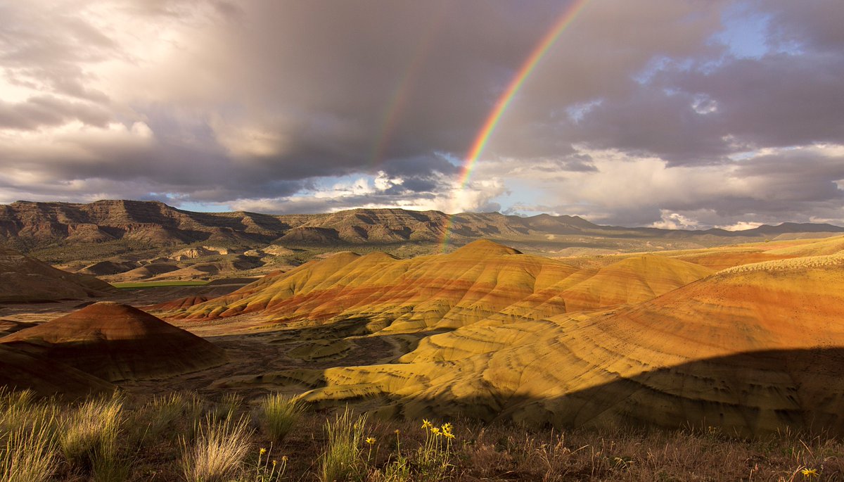 A double rainbow over a colorful geologic landscape