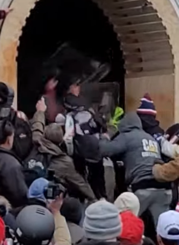 MalagaBridget's tweet photo. @SeditionHunters In this video, #CranOceanSprayer hits police with shield repeatedly and throws it at them. He then moves away from tunnel, turns his hat around and puts on goggles. See him moving toward police with shield beginning 0:32 https://t.co/99ROd8hBZ0 https://t.co/WXF9sYvb9C