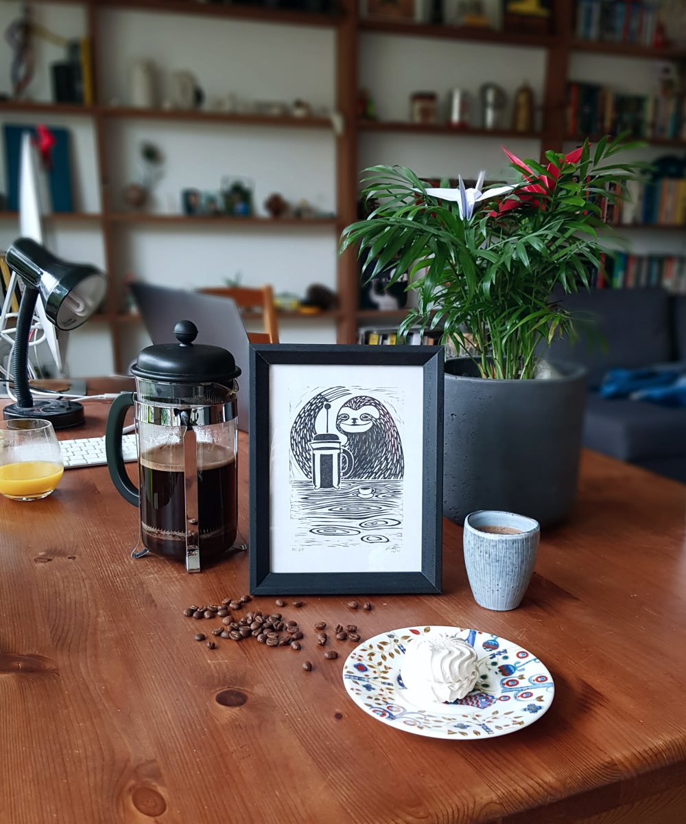 Black and white linocut print of a sloth using a French press to make coffee