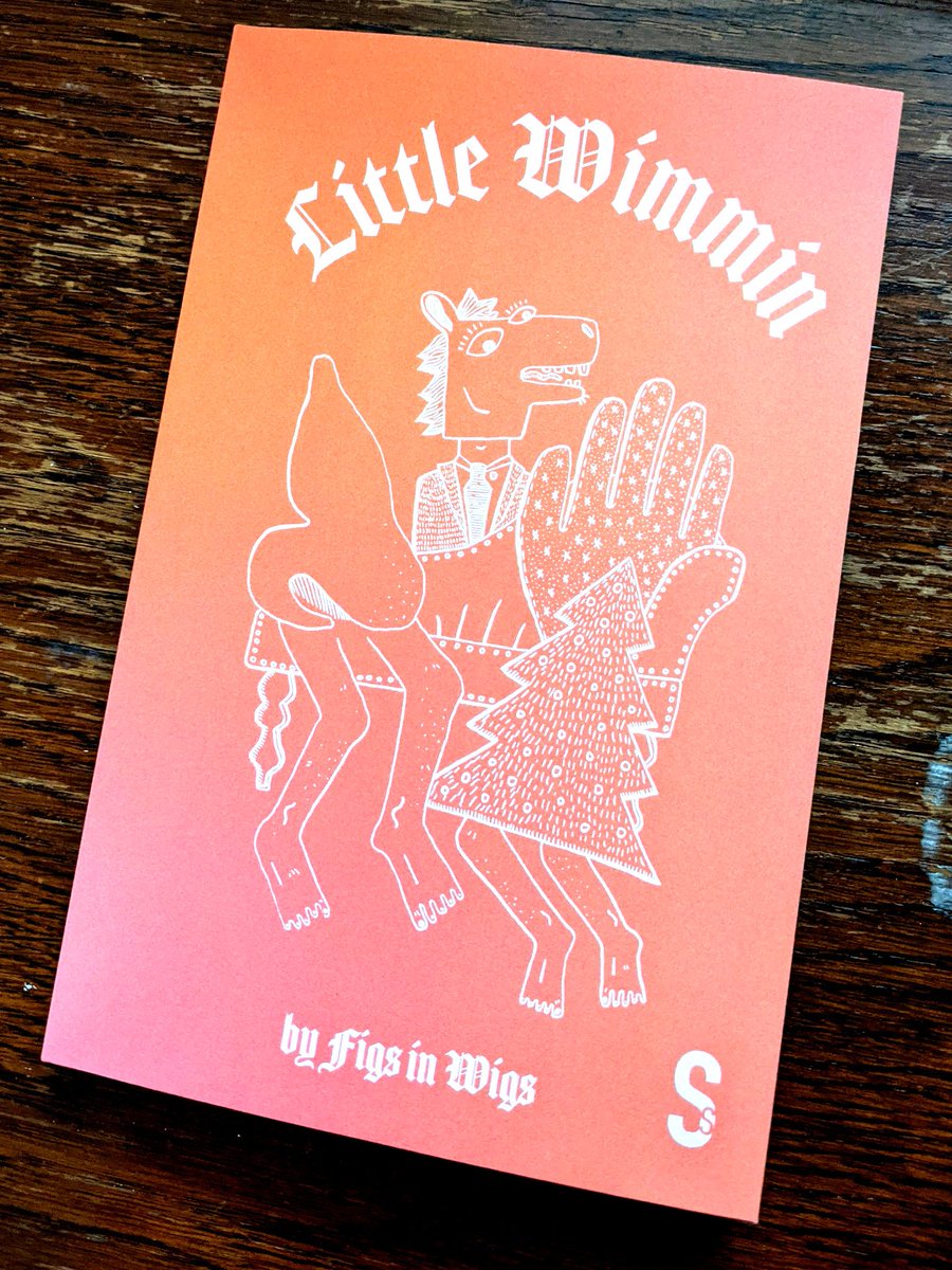 A copy of the book Little Wimmin by Figs in Wigs on a rather battered wooden tabletop.