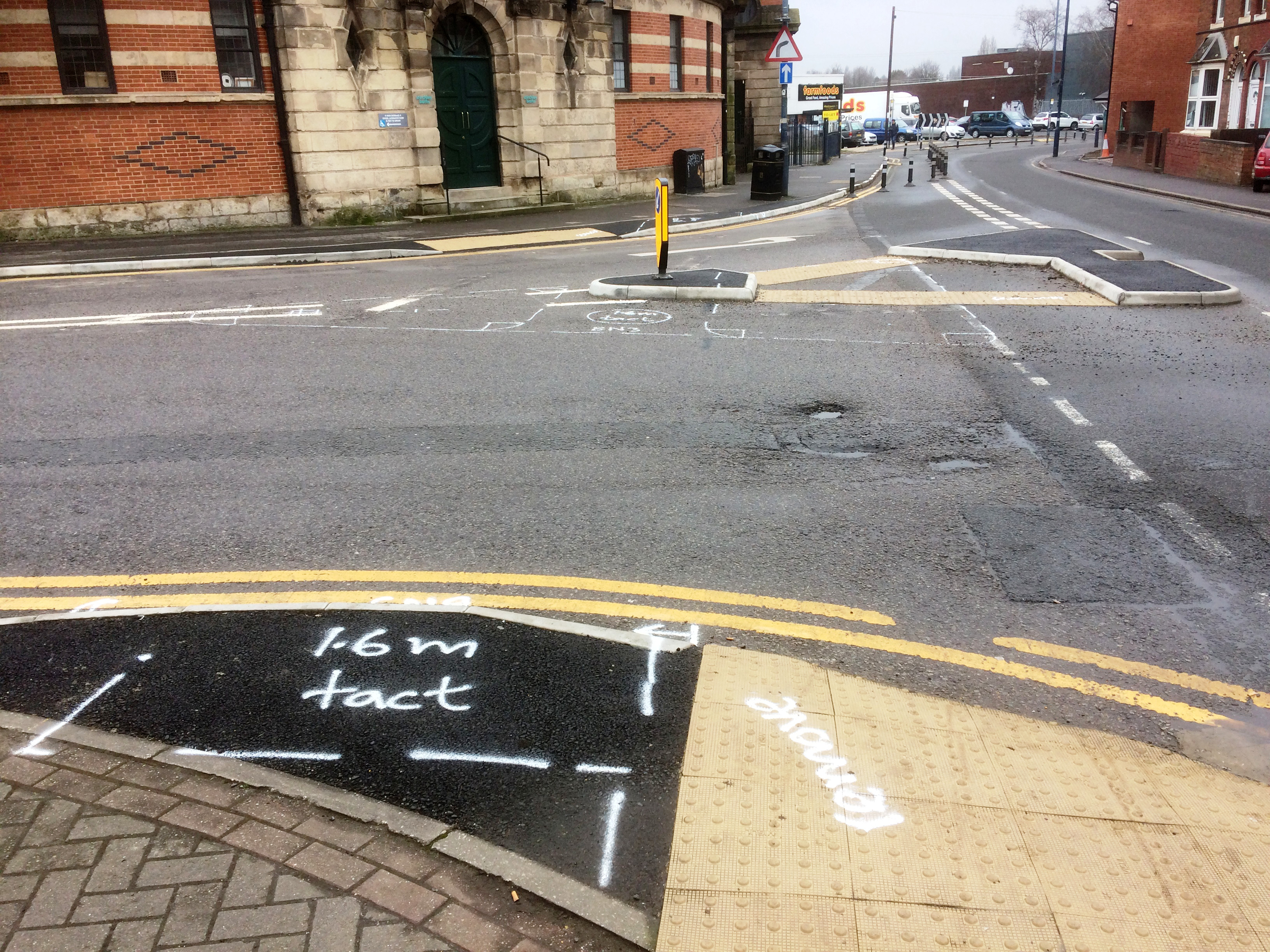 A pedestrian refuge at a road junction, with pavement markings indicating that it is to be moved