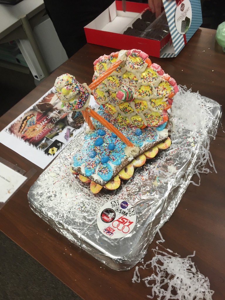 Celebratory cake made to look like the James Webb Space Telescope, created by Sarah Wright. There are many colorful sprinkles on top of the cake's "mirrors" and "sunshield." Photo by Nick Bond.