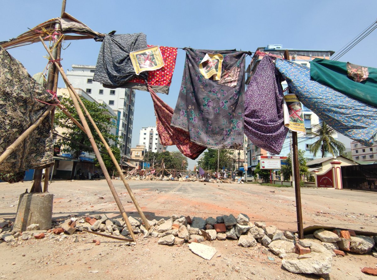 Myanmar_Now_Eng's tweet photo. 1 / 3 One of the newest resistance strategies used by anti-coup protesters is to delay the advance of security forces by hanging htameins- women's sarongs- across the roads. The photos below illustrate how protesters in Yangon’s Thaketa Township employ this tactic. https://t.co/JcrtjjdFve