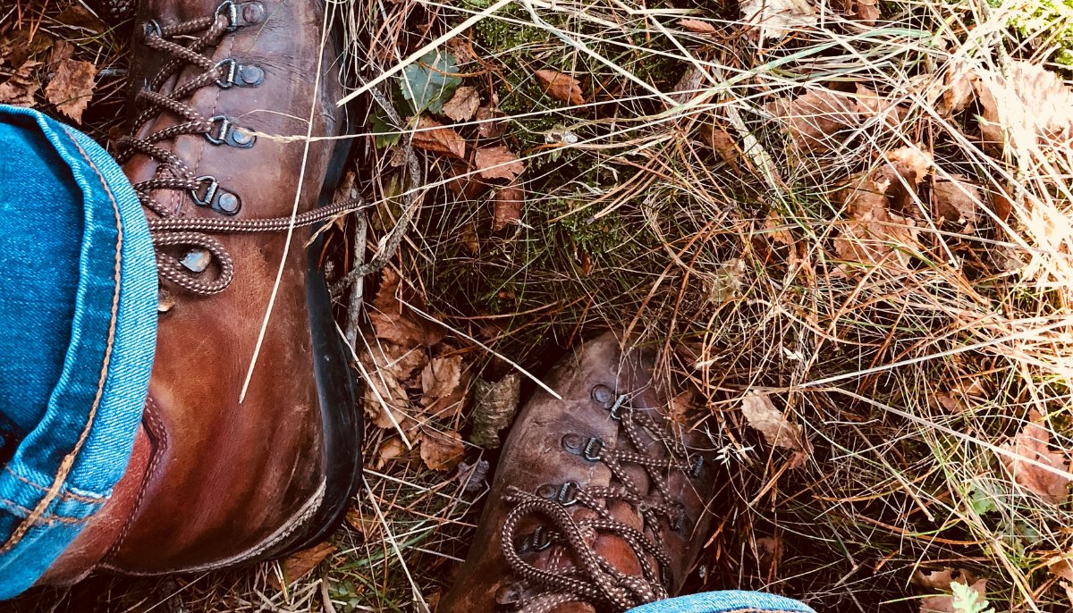 Top down view of leather boots stepping into grass