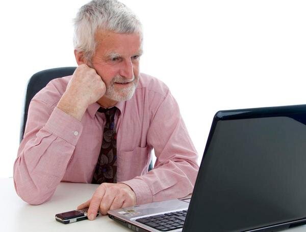 В скромно обставленном кабинете сидел пожилой человек. Пожилые за компьютером. Пенсионеры с ноутбуком. Старик за компьютером. Пожилой человек за компьютером.