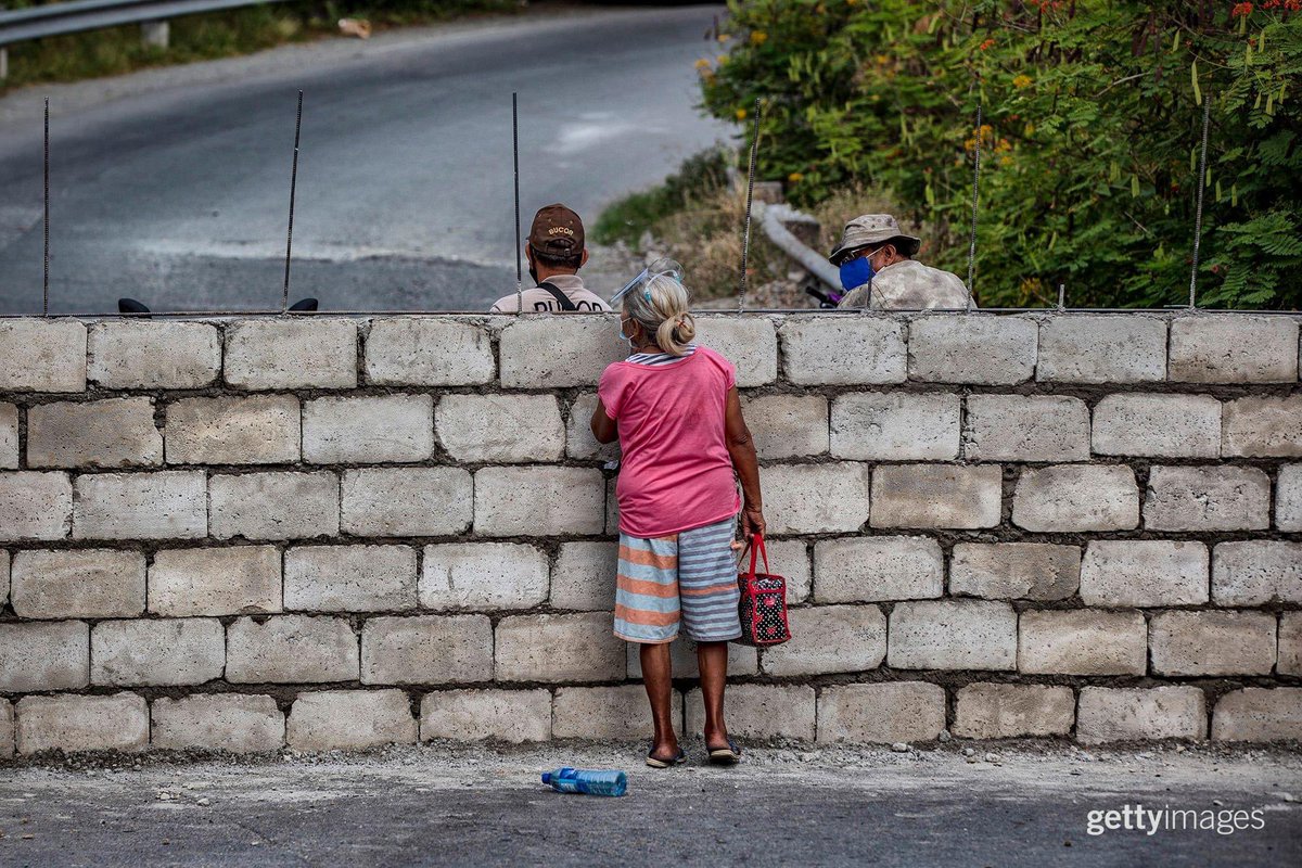 A resident peeks over a concrete wall erected in the middle of a road in Muntinlupa, March 21, 2021. The wall was erected to stop the spread of COVID-19 in the area and in a nearby prison, but it has essentially trapped residents of a village who need the road to access the city.