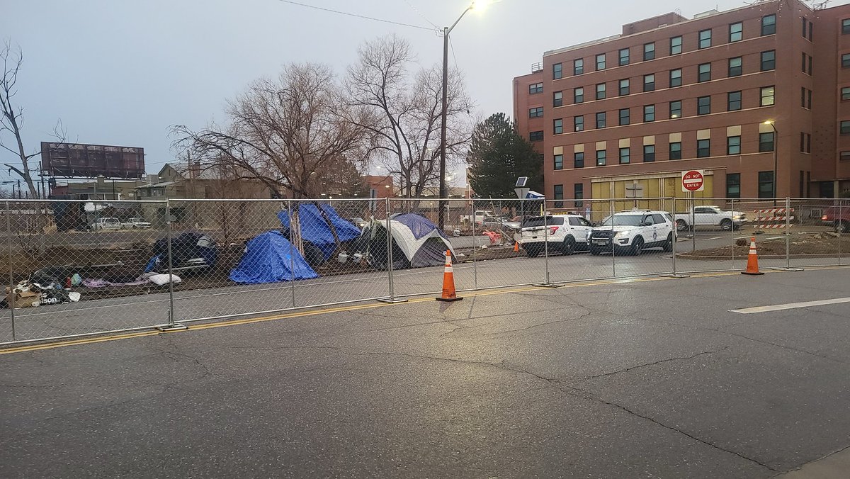 userjame's tweet image. 25+ Denver Police officers have shut down 3 city blocks with fences downtown. The posting claims this is an "encumbrance removal" despite clear passage on all sidewalks. 

Dozens of residents are at risk of displacement and the destruction of their belongings.  
#denverprotests