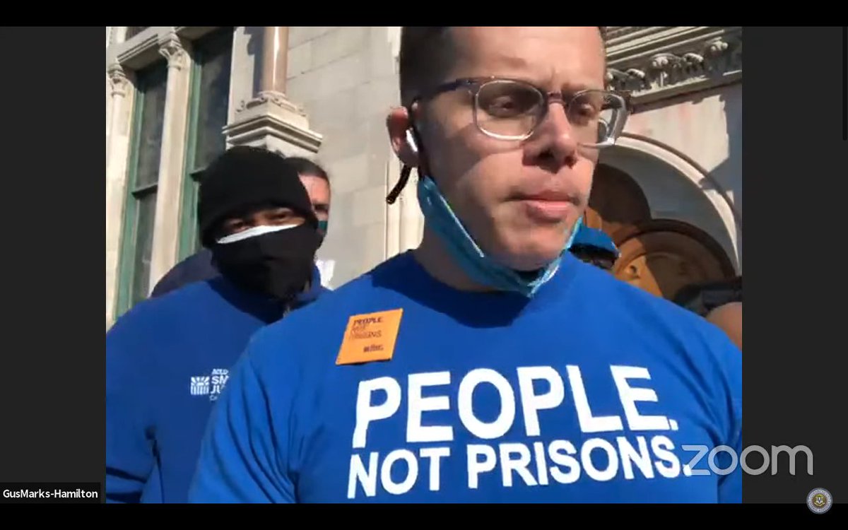 Screenshot of Gus Marks-Hamilton testifying in support of Clean Slate. He is wearing a blue shirt that says "People. Not prisons." Smart Justice Leaders in the background with mask. 