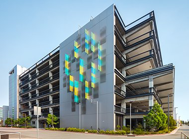 In addition to being a mixed-use #mobilityhub, this parking structure at Menlo Gateway also boasts some impressive #publicart. Dichroic glass on the shear walls changes colors depending on lighting. Take a look: ow.ly/jam350DXzCh