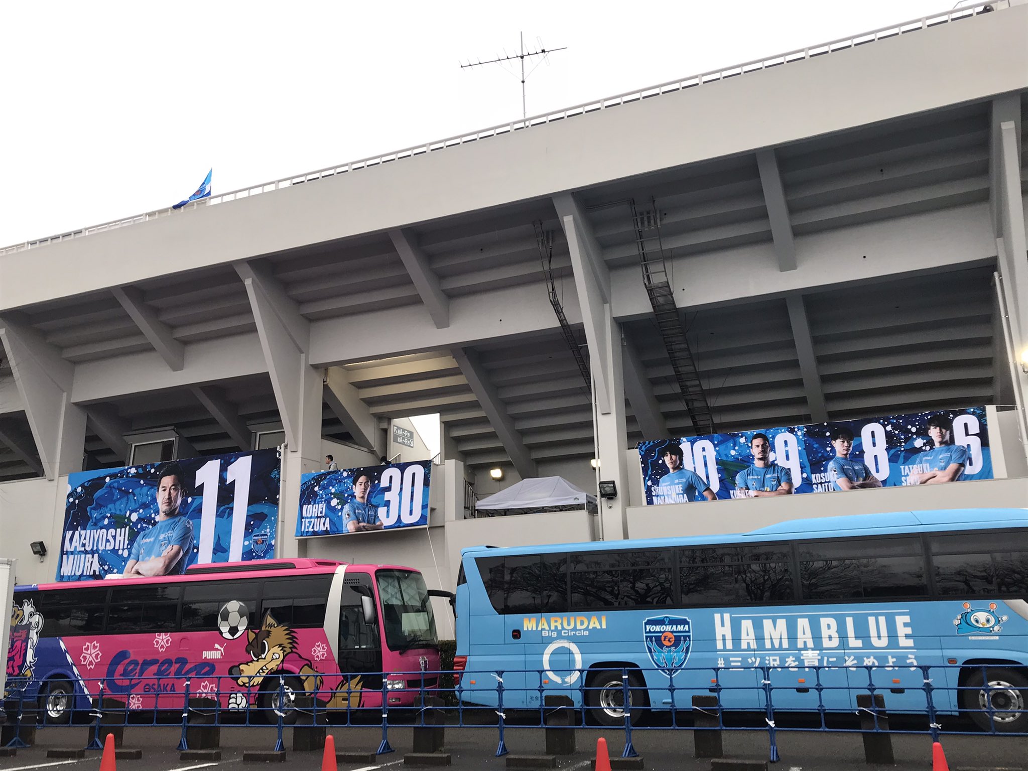 浅野有香 Yuka Asano 今日の試合を写真でプレイバック 21 3 13 J1第4節 横浜fc C大阪 ニッパツ三ツ沢球技場 両チームの選手バスがならぶ正面玄関エリア 今シーズンの大きな選手バナーをバックにフリ丸さん Yokohamafc フリ丸 Cerezo